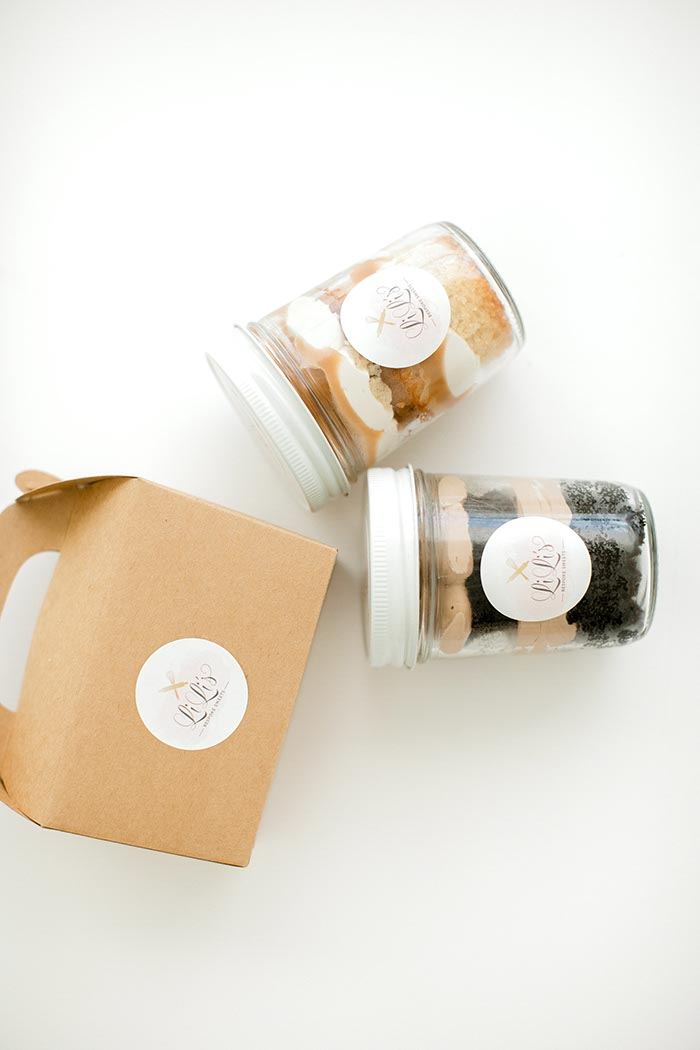 Cake jars with branded lids beside a gift box