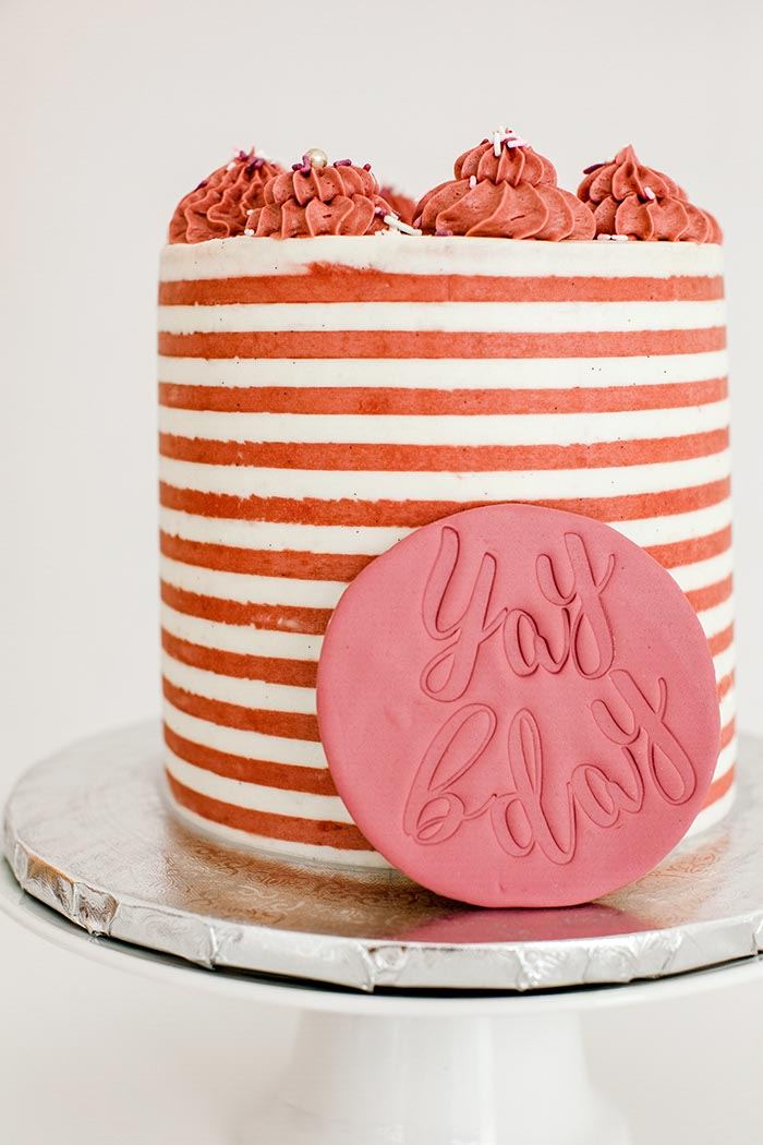 Coral and white striped buttercream birthday cake with a yay bday plaque
