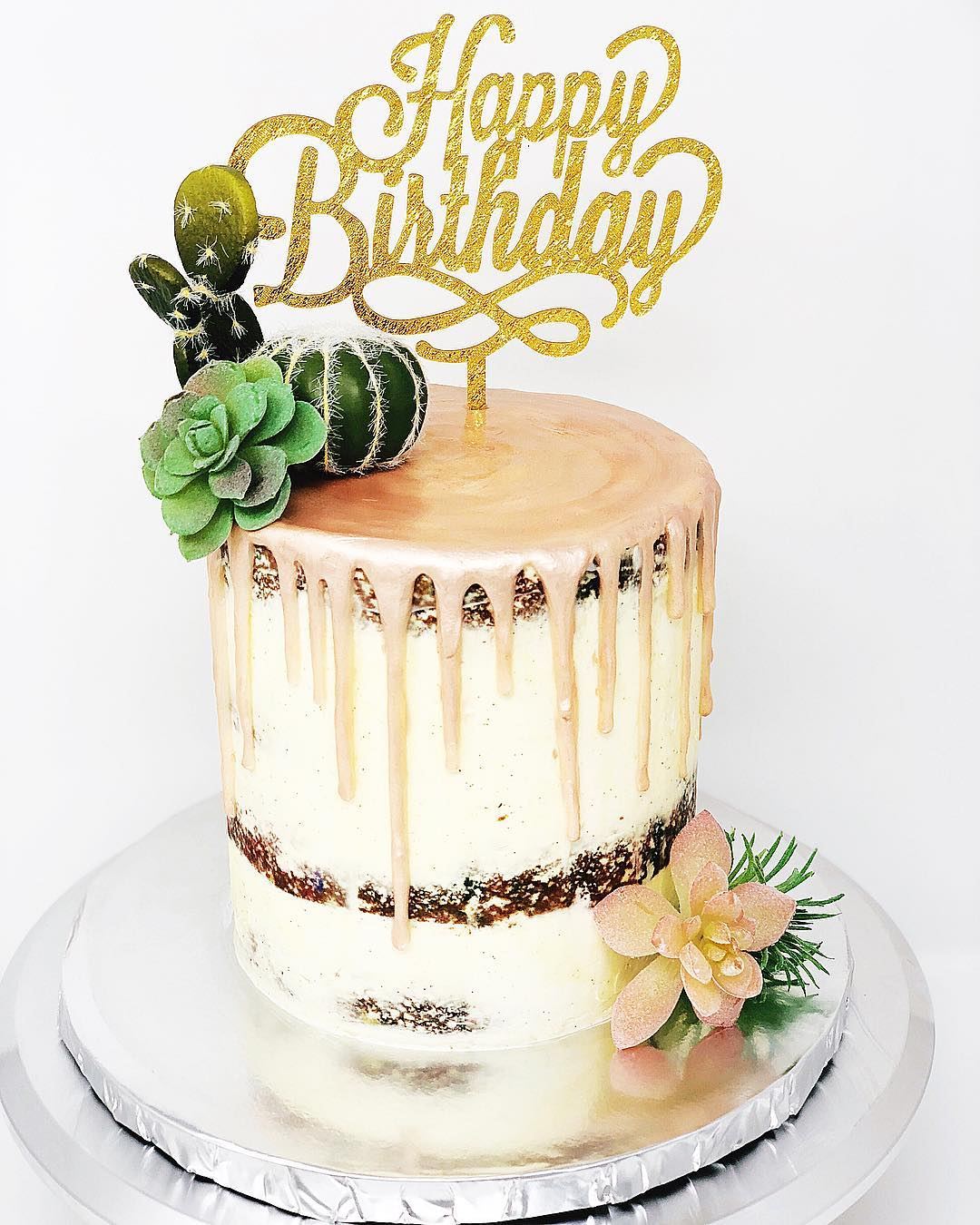 Drip cake with a gold Happy Birthday topper and succulents
